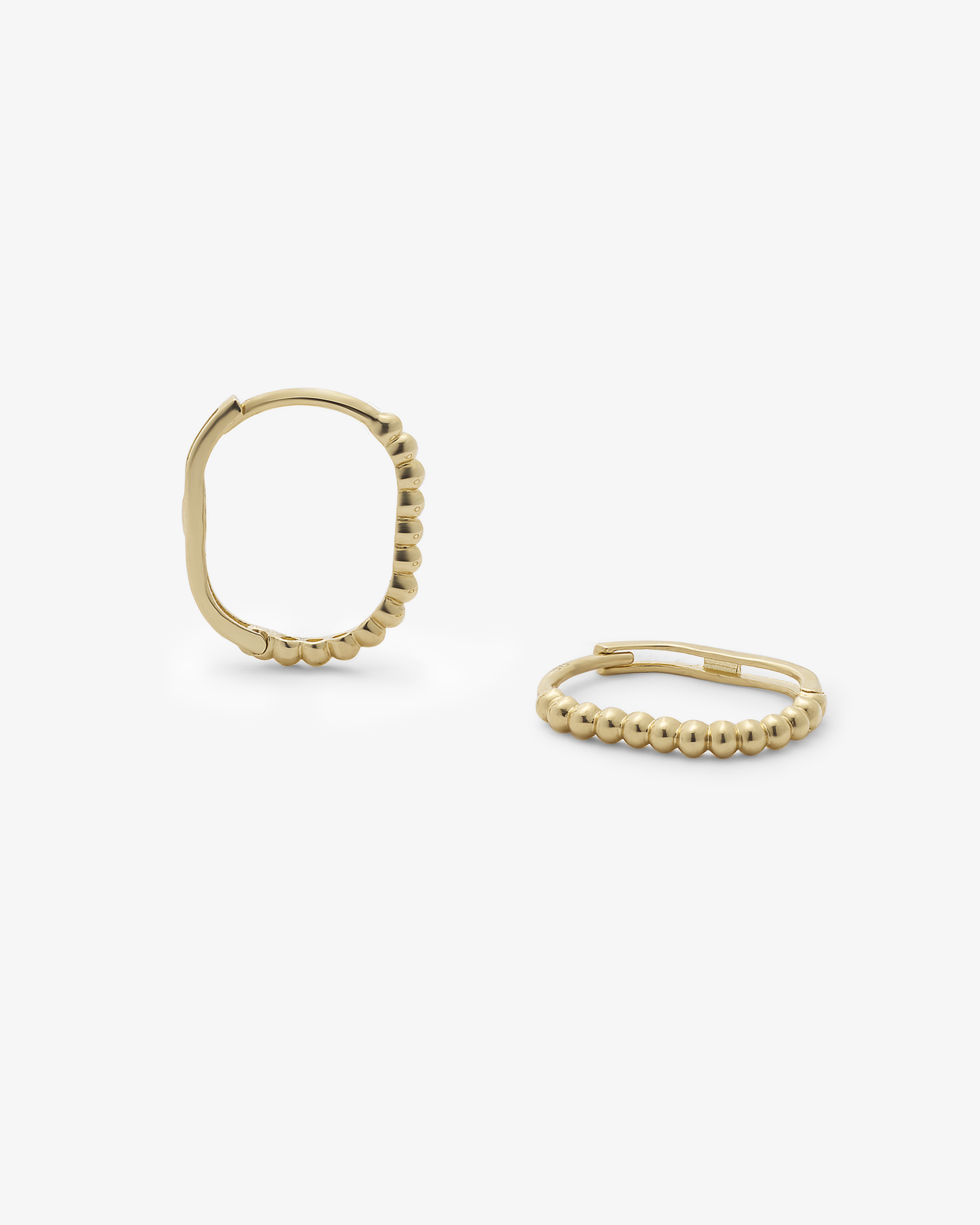 Gold huggie earrings on a white background